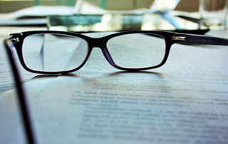 image of glasses sitting on a stack of papers