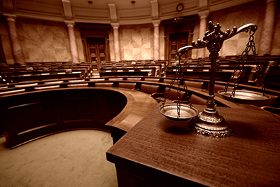 An image of court room scales of justice with a traditional courtroom in the background.