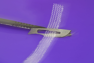 Image of a scalpel cutting through a piece of surgical mesh