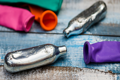 Image of small nitrous oxide tanks (whippets) and balloons.