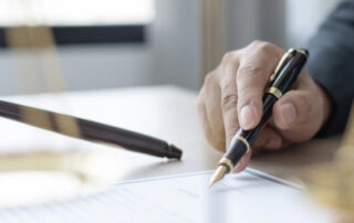 person with pen signing legal documents