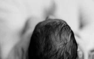 Black and white photo of a person holding a newborn baby.